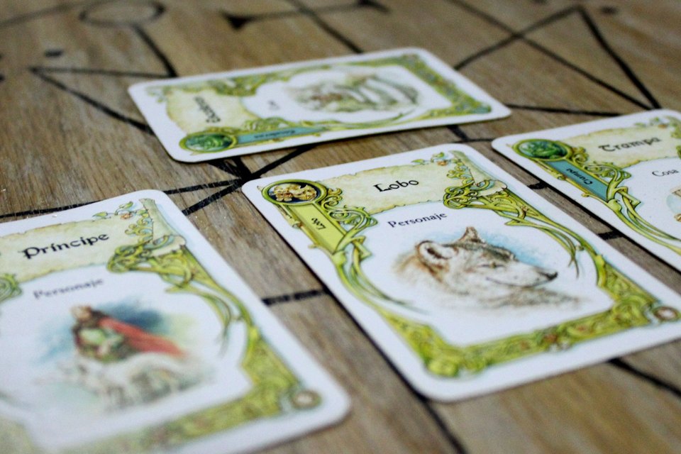 Once Upon a Time storytelling cards, Spanish edition, laid out on a wooden table with the Prince, Wolf and Trap cards in view